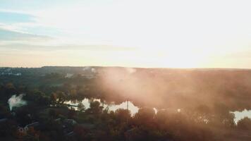 smoke are enveloping a river as a result of a fire after a drought on the background of power station into the distance. Aerial view video