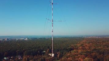high telecommunication antenna on the background of forest and cityscape. Camera motion up video