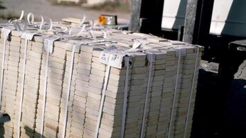 an automatic trolley is stacking pallets with bricks next to each other in the street near the factory. Professional warehouse equipment video