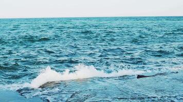 Crests of the waves are breaking on the reefs near the shore in the summer. Seascape. Slow motion. Aerial view video