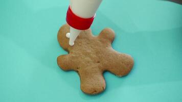 The process of making New Year's cookies in the form of a man on light background. Ginger man. Decorating products with using pastry bag. Close-up video