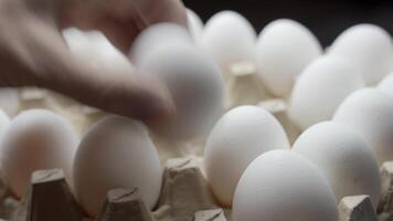 Close view of a farmer taking eggs from a pile and placing them into a carton to be sold video