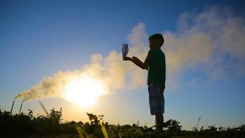 Kid Playing With Paper Airplane. Happy kid playing with paper airplane in the sunset near air pollution video