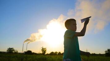 Paper Plane In Children Hand. Adorable little boy holding a paper plane near factory video