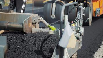 professional equipment is mixing bitumen and putting the mixture on the road on the background of a passing roller machine video