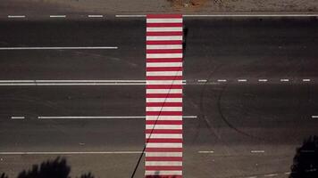 trucks are driving on the highway with a pedestrian crossing in red and white colours. Aerial view video