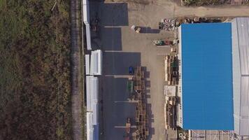 trucks are transporting apples on trailers in the territory of warehouse with wooden boxes near an apple orchard in the field. Aerial view video
