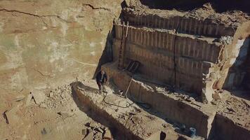 worker is drills stones with using pneumatic tool in the sand quarry. Camera motion up. Aerial view video