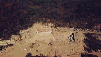 people are walking near sand quarry with the stones below. View of the quarry with the forest. Camera motion up video