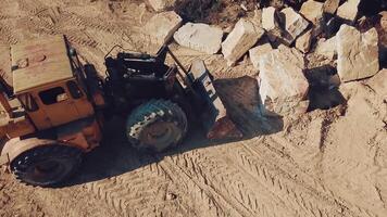 specially equipped bulldozer with a jug is picking up a stone in the quarry on the background of a rock with a forest. View of the sand quarry. Camera motion up. video