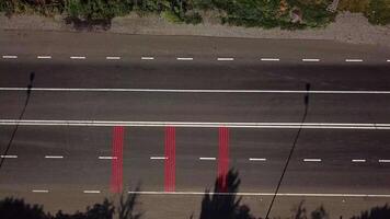 cars are passing on the road with red markings and with a pedestrian crossing. Aerial view. Camera motion to right video