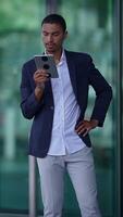 A stylish businessman confidently using a tablet while in a modern and vibrant environment video