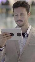 un elegante hombre es disfrutando el utilizar de un tableta en un moderno y contemporáneo ajuste hoy video