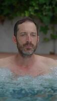 A contemplative man finds himself in a tranquil pool surrounded by lush and vibrant greenery video
