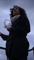 A contemplative woman is holding a piece of ice while standing in dramatic weather conditions video