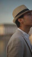 A Stylish Man in a Hat by the Water, embodying confidence and charm in a picturesque setting, video
