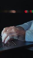 Focused hands are actively typing on a laptop within a low light environment or setting video