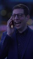 A cheerful person is smiling while talking on the phone during the dusk hours in the city video