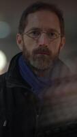 A thoughtful man with glasses and a beard is in an urban setting, conveying calm introspection video