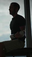 The striking silhouette of a man lifting a dumbbell in a wellequipped gym setting video