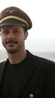 A striking pilot portrait donning a crisp uniform set against a stunning scenic background video