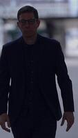 A mysterious figure dressed in a dark suit is seen walking in a captivating urban environment video