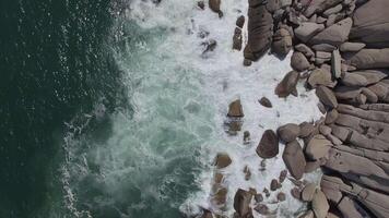 View from a drone vertically down on a stone cape washed by strong waves video