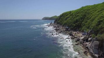 Stunning rocky seashore with clear water and greenery. Rolling waves create foam video
