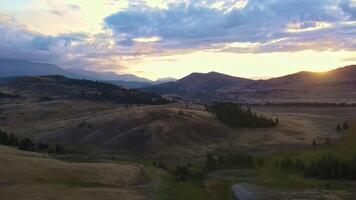 Aerial. hills, dirt roads on hillsides, coniferous trees at colorful sunset video