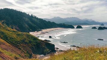 Cannon Beach Coastal cliffs and sandy beach with ocean waves. A scenic coastal landscape with rocky cliffs and a long sandy beach, where gentle ocean waves meet the shore. video