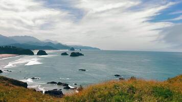 Coastal view of ocean and distant rocky formations. A stunning coastal view with waves gently crashing along the shore, and rocky formations emerging from the water in the distance. video