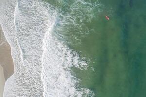 Aerial view of sandy beach and ocean with waves surfer waiting for the good wave photo