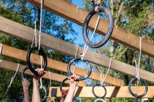 Hands grasp a rings at a hanging obstacle in an OCR obstacle course photo