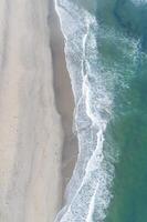 Beautiful white empty beach and sea waves seen from above. photo