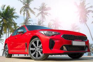 Red car on a background of palm trees. Stylish, modern, bright image of the car for design solutions. photo