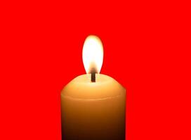 A single burning candle flame or light glowing on a big white candle isolated on red background with clipping path photo