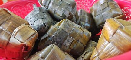 Ketupat or rice dumpling packed inside a diamond-shaped container of woven palm leaf pouch. Special dish served at Eid Mubarak Ied Fitr celebration in Indonesia photo