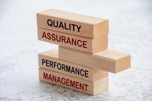 Quality Assurance and Performance Management text on wooden blocks. Business and quality assurance concept photo