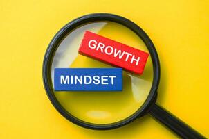 Top view of Growth Mindset text on multicolored wooden blocks with magnifying glass background. Business strategy concept. photo