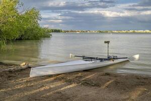 Coastal rowing shell on a shore of Boyd Lake in northern Colorado in late spring or summer scenery. photo