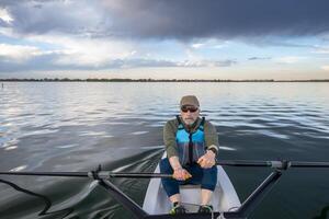 senior man in a rowing shell on a calm lake in Colorado photo
