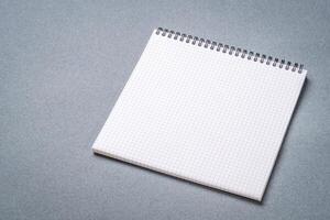 blank spiral notebook with grid paper on a textured, gray paper photo