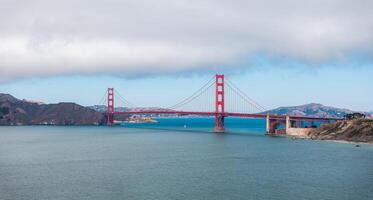 Golden Gate Bridge with Sailboat and Cloudy Sky in San Francisco Bay photo