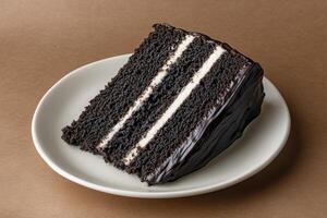 An inviting slice of rich chocolate cake sits on a white plate, showcasing layers of decadent chocolate and creamy frosting. Perfect for dessert lovers seeking indulgence. photo