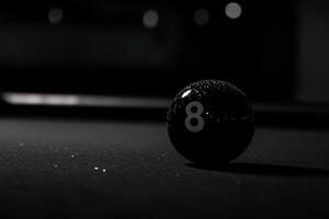 A solitary black snooker ball rests on a dark table, adorned with a single droplet of water. Soft lighting accentuates its smooth surface, highlighting the balls iconic number. photo