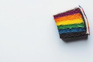 Brightly colored layers of a rainbow cake are showcased from above, displaying vivid hues of red, orange, yellow, green, blue, and purple, with a simple white background enhancing its vibrancy. photo