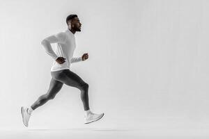 A dedicated runner showcases his athleticism while sprinting confidently across a clean white backdrop. The focus is on his form and movement, highlighting his commitment to fitness. photo