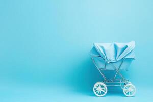 A light blue baby carriage is positioned against a clean, solid background, creating a visually appealing and serene atmosphere. The carriage features a simple design and sturdy wheels. photo