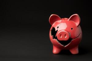 The broken piggy bank showcases critical damage, with cracks exposing its interior. It rests on a clean, solid black surface, highlighting the need to fix and collect its contents. photo