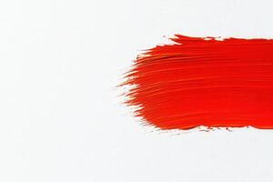 A dynamic application of bright red paint demonstrates bold brush strokes on a pristine white surface, showcasing artistic expression and color contrast. photo